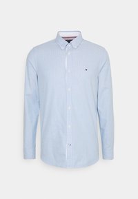 Chemise bleu clair à manches longues, boutonnée, avec col boutonné et petit logo brodé sur la poitrine gauche.