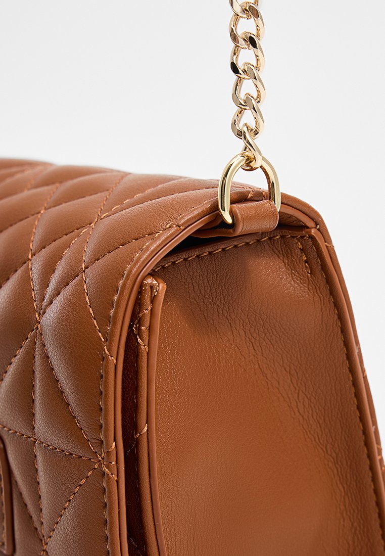 Sac à main en cuir matelassé marron avec une bandoulière en chaîne dorée. Le sac présente une forme structurée et une texture lisse, mettant en avant son design élégant.
