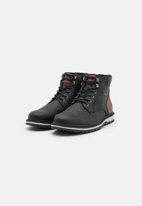 Botas de cuero negro con acentos marrones, diseño con cordones, forro de pelo sintético, suela de goma y entresuela blanca contrastante.