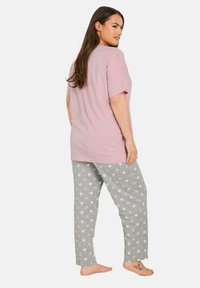 Grå pyjamasbyxor med ljusrosa hjärttryck, kombinerat med en löst sittande rosa t-shirt med korta ärmar och rak skärning.