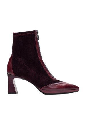 Stivaletti bordeaux con punta affusolata, superiore in suede e chiusura con zip. Il tacco è di forma quadrata con un accento argentato texturizzato.