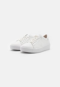 Weiße Sneakers mit einem Obermaterial aus glattem Leder, runder Zehenpartie und strukturierter Gummisohle. verfügen über Schnürsenkel und minimale Nähte für ein sauberes Design.