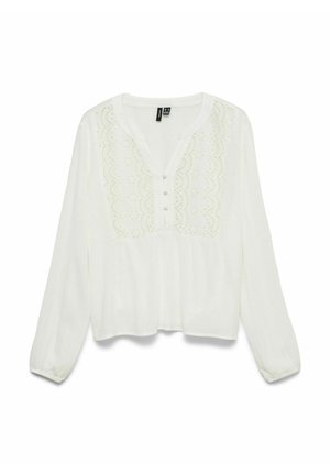 Vit blus med långa ärmar och spetsdetaljer på bröstet, små tygknappar och en rundad halsringning med en kort knappslå.