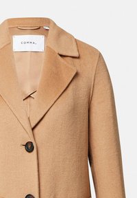Cappotto in lana color cammello con ampi rever, due bottoni scuri e fodera beige, etichettato "COMMA" all'interno del colletto.