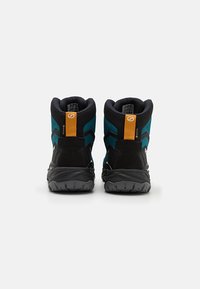 Bottines de randonnée hautes noir et bleu canard avec des accents orange, dotées d'une tige en tissu texturé et d'une semelle extérieure en caoutchouc robuste pour la stabilité.