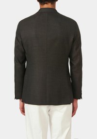 Giacca da abito grigio scuro con taglio dritto, rever a punta, spacco singolo e maniche lunghe con bottoni decorativi. Sotto sono visibili pantaloni bianchi.
