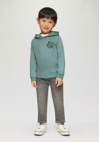Lichtgroene hoodie met een zwarte ruimteprint, gecombineerd met grijze jeans en witte sneakers met grijze accenten. Ontworpen voor kinderen.