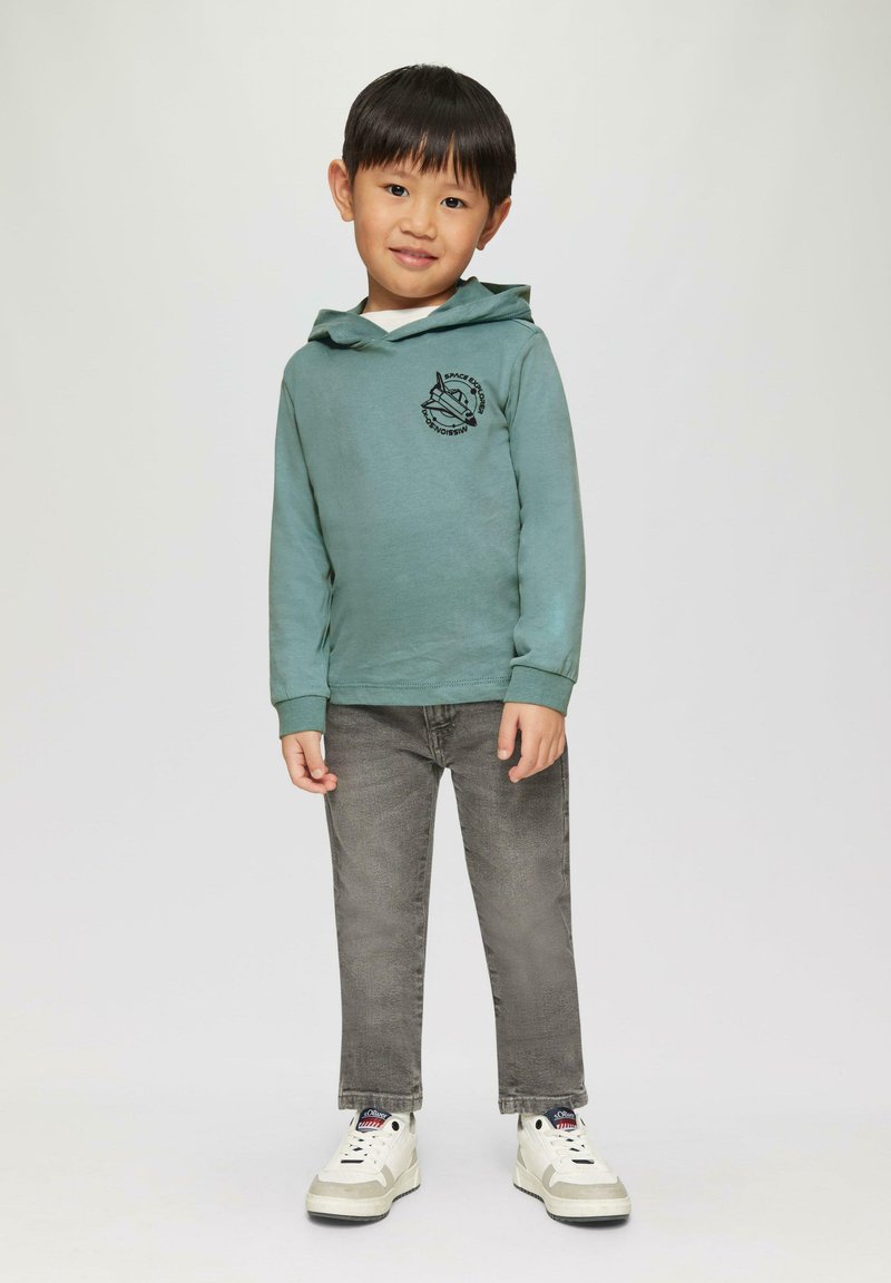 Lichtgroene hoodie met een zwarte ruimteprint, gecombineerd met grijze jeans en witte sneakers met grijze accenten. Ontworpen voor kinderen.