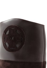 Stivali in pelle marrone e suede con un design a ritaglio rotondo nella parte superiore. Presenta una texture liscia e cuciture dettagliate lungo le cuciture.