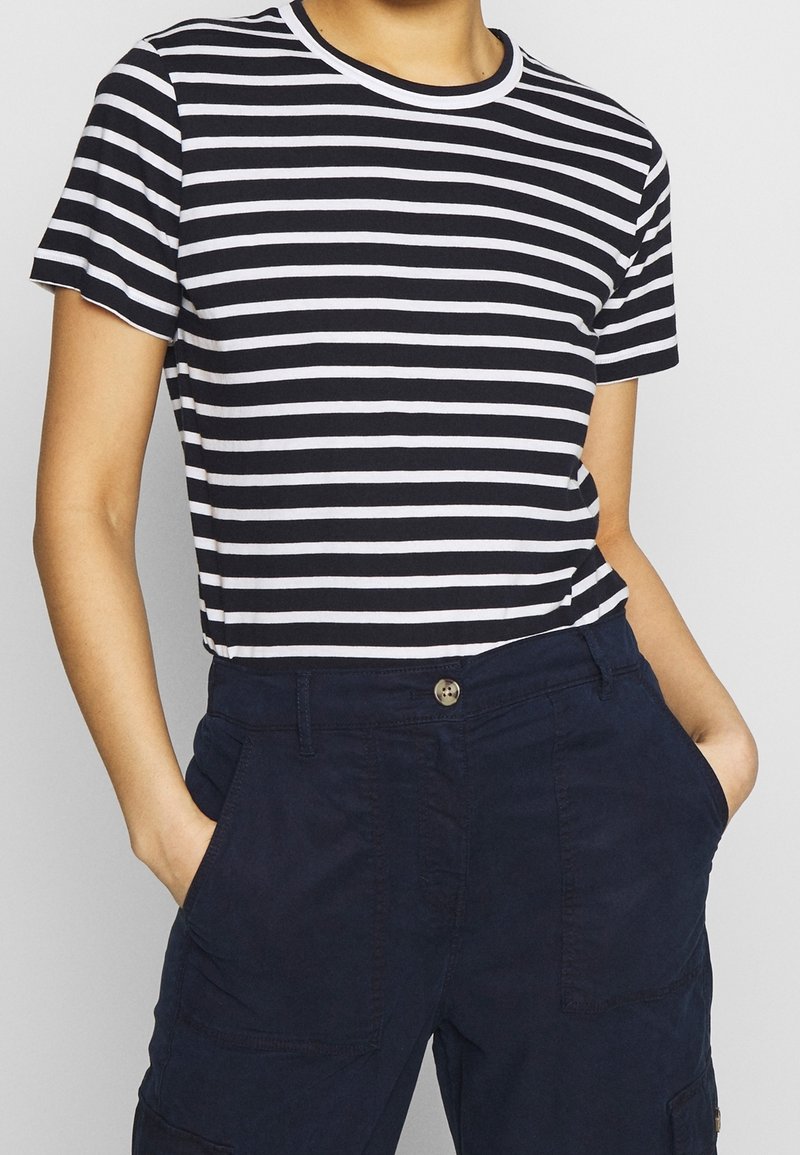 T-shirt a righe blu scuro e bianche con collo rotondo e maniche corte, abbinata a pantaloni blu scuro con tasche laterali.