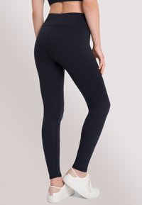 Leggings a vita alta di colore blu navy, realizzati in tessuto elasticizzato con una texture liscia; presentano cuciture piatte che offrono una vestibilità affusolata.