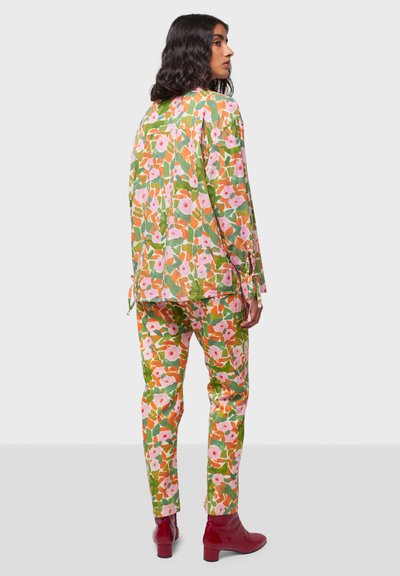 Completo con stampa floreale caratterizzato da una combinazione di colori verde, rosa e arancione. Top morbido con maniche lunghe, abbinato a pantaloni aderenti coordinati.