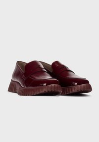 Bordeaux leren loafers met een ronde neus en een rubberen gegroefde zool. Kenmerkt zich door een gestikte afwerking over de bovenkant. Gladde en glanzende textuur.
