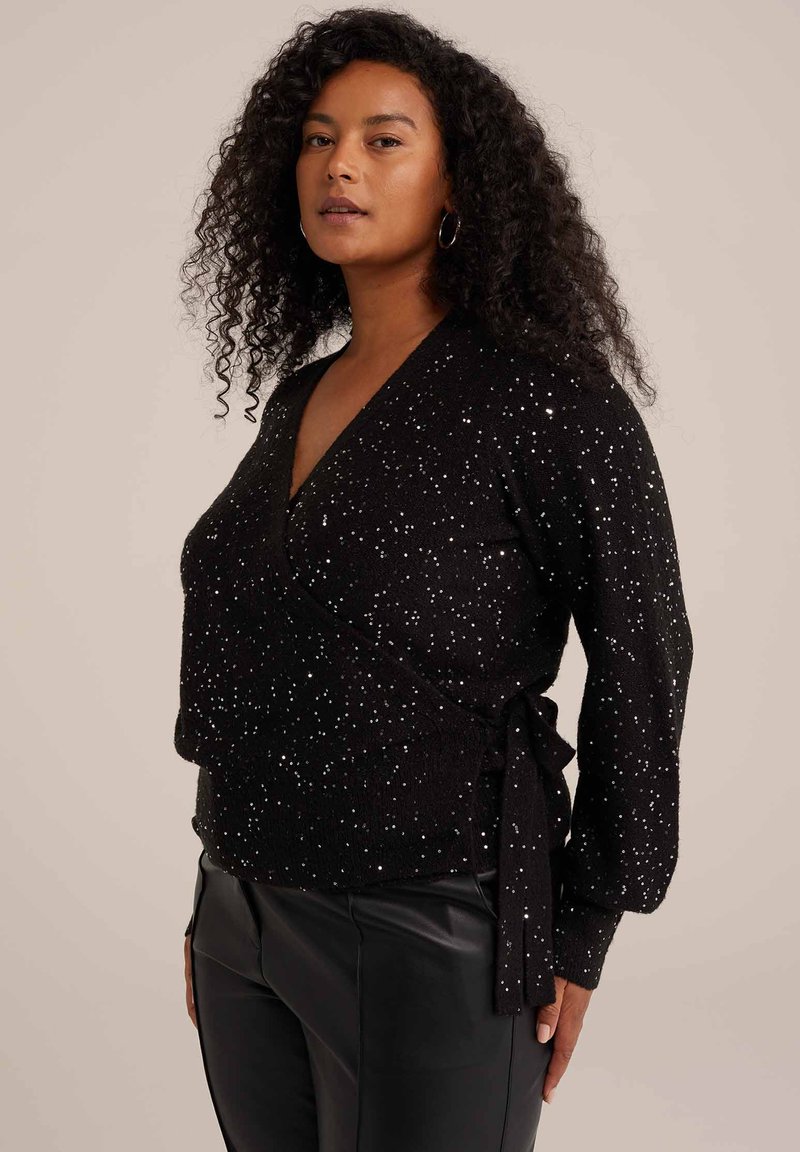 Črna ovita jopica z belimi piko, obliko V, dolgi rokavi, teksturirana tkanina, stranska zanka, kombinirana z črnimi hlačami iz umetnega usnja.