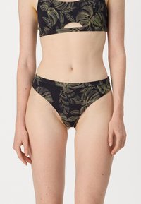 Maillot de bain noir avec un motif de feuilles en vert et jaune, comprenant un haut court avec des découpes et un bas taille haute assorti. Texture lisse.