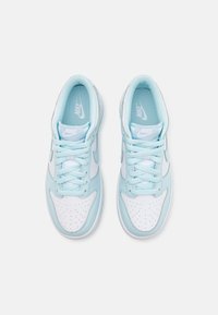 Nike tenisice od svjetloplave i bijele sintetičke kože. Karakteristike uključuju perforirani vrh, vezanje uzice i potpisani logo na jeziku.