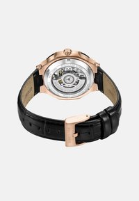 Roze gouden roestvrijstalen horloge met een transparante achterkant, zwart leren band met een gestructureerd patroon en een roestvrijstalen sluiting.