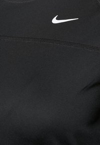 Maglietta sportiva nera realizzata in tessuto morbido. Presenta un logo Nike swoosh bianco e una cucitura sul petto.