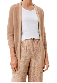 Lätt beige cardigan med öppen front, texturerad stickning och trekvartslånga ärmar, i kombination med mönstrade tanbyxor med bladdesign.