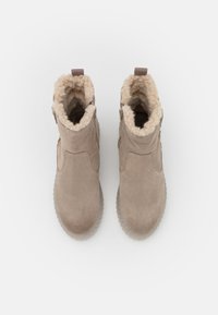 Botas de tobillo de ante beige con revestimiento de pelaje sintético, punta redonda y suela de goma texturizada. Cremallera lateral para un acceso fácil.