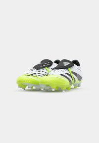 Bottes de football blanches et vert néon avec des accents noirs et une tige texturée, comportant des crampons pour l'adhérence et un design épuré.