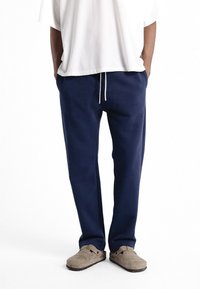 Pantalons de survêtement bleu marine à coupe décontractée, dotés d'une taille à cordon, d'un tissu doux et d'un resserrement aux chevilles. Poches latérales incluses.