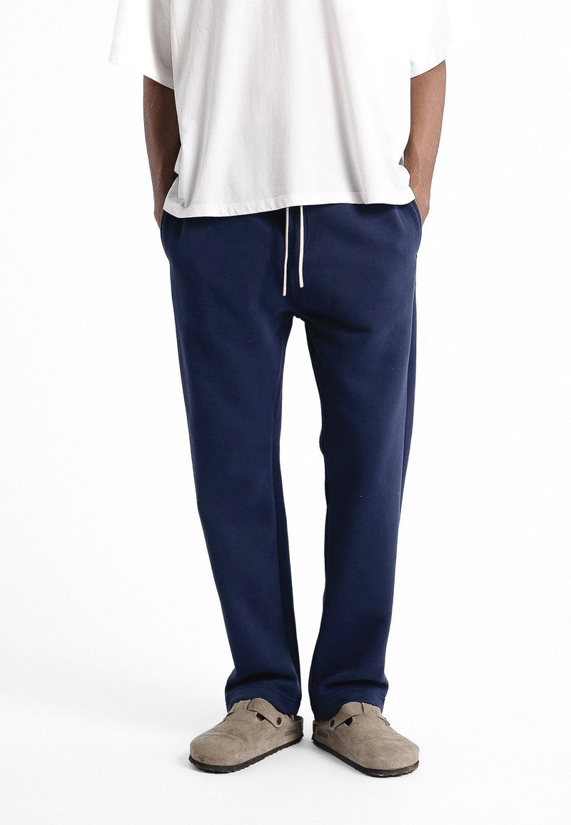 Pantalons de survêtement bleu marine à coupe décontractée, dotés d'une taille à cordon, d'un tissu doux et d'un resserrement aux chevilles. Poches latérales incluses.