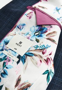 Tkanina w kwiatowy wzór z niebieskimi i różowymi kwiatami, połączona z granatowym materiałem teksturowanym. Zawiera metkę z napisem "NEXT", rozmiar 40R oraz "SLIM FIT."