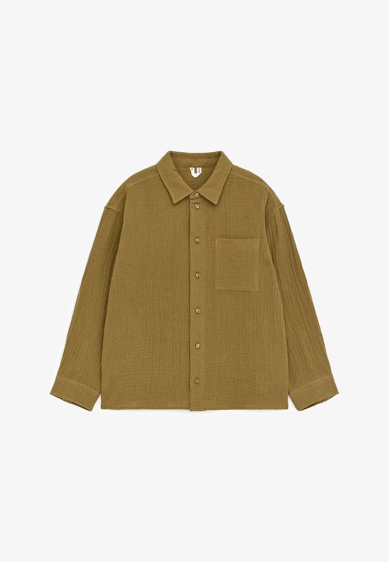 Chemise verte olive à manches longues avec boutons, col pointu et une poche poitrine, posée à plat sur fond blanc.