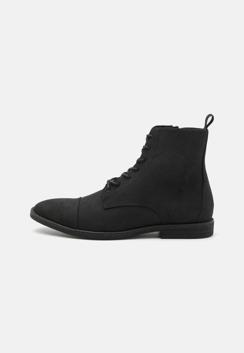 Botte noire à lacets montante avec talon bas, fermeture éclair latérale et languette, présentée sur un fond clair uni.