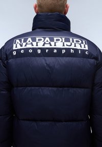 Marineblauwe pufferjack met groot wit "NAPAPIJRI" logo op de achterkant. Gemaakt van glanzend materiaal met een doorgestikt patroon en hoge kraag.