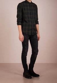 Tmavě zelená kostkovaná košile s límečkem, spárovaná s ošoupanými černými skinny džíny a černými semišovými kotníkovými botami.