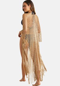 Gehaakte strandcover-up, gemaakt van lichtgewicht beige materiaal, heeft een open gaasontwerp, lange mouwen en een franjerand voor extra detail.