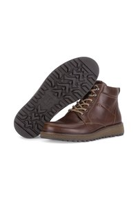 Bruine leren enkellaarzen met vetersluiting, een gestructureerde rubberen zool en contrasterende lichtbruine accenten op de tussenzool en het stiksel.