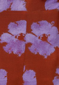 Textil mit Struktur zeigt einen rostfarbenen Hintergrund mit großen lila Blumenmustern, die Nuancen von Lavendel und tiefen lila Akzenten präsentieren.