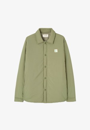 Chaqueta acolchada verde claro con cuello tipo solapa, cierre de botones a presión y una etiqueta de marca cuadrada en el pecho. Textura suave, diseño casual.