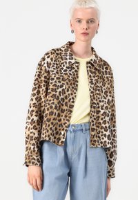 Traper jakna s leopard uzorkom, sa ovratnikom, prednjim dzepovima i slobodnim krojem, složena preko svijetložute majice.