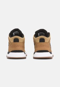 Las zapatillas Timberland cuentan con una parte superior de tela en tonos marrón y negro, con un cuello acolchado en el tobillo, una entre suela blanca y una suela de goma. Marca en el talón.