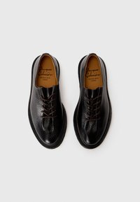 Black leather shoes with a textured finish, rounded toes, brown laces, and contrasting stitching. Interior features a branded insole.