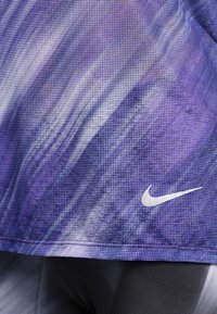 Paarse en zwarte sportstof met structuur en een wit Nike-swooshlogo aan de rechterbenedenkant.