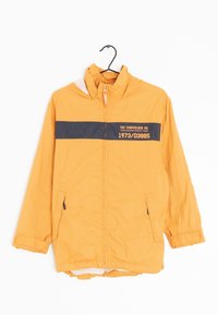 Gul Timberland-jacka med huva, svart horisontell rand och text, dragkedja fram och framfickor, hängande på en svart galge.