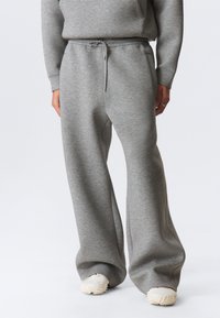 Light gray wide-leg sweatpants made from soft fabric with an elastic waistband, drawstring detail, and side pockets.