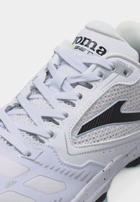 Λευκό αθλητικό παπούτσι με δίχτυ σε πλαϊνά μέρη, μαύρο λογότυπο και λευκά κορδόνια δεμένα πάνω σε επενδεδυμένη γλώσσα με ορατό το όνομα της μάρκας.