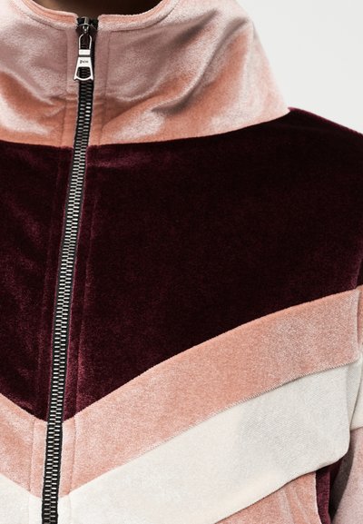 Βελούδινο τζάκετ με φερμουάρ και ψηλό γιακά, με σχεδιασμό σε χρώματα μπέργκουντι, ροζ και κρεμ, με υφή υφάσματος και μεταλλικό φερμουάρ.