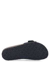 Suela de goma texturizada negra con un patrón de tracción en forma de flecha, bordes reforzados y una pequeña correa en el costado. El material parece duradero y flexible.