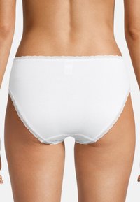 Weiße Baumwollslips mit einem gewellten Spitzenrand. Der Stoff wirkt glatt, und das Design hat eine klassische Form mit voller Abdeckung.