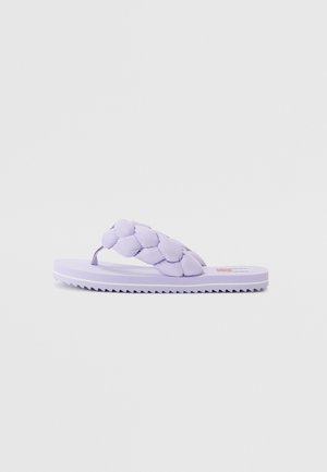 Lila flip-flop dengan tali yang empuk dan anyaman, sol datar, dan bagian bawah yang bertekstur untuk genggaman. Desain sederhana dengan label yang menampilkan logo.