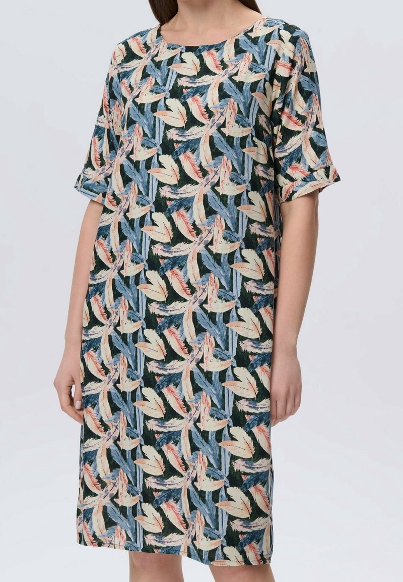 Femme portant une robe longueur genou avec des manches longueur coude présentant un motif abstrait de feuilles en bleu, beige et corail.