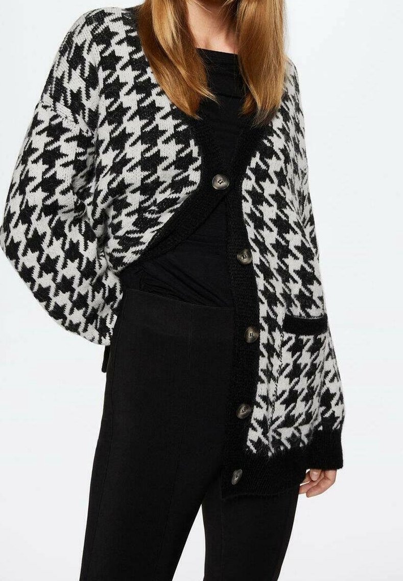 Černobílý cardigan s kostkovaným vzorem houndstooth, s výstřihem do V, knoflíky vpředu a kapsou na pravé straně.