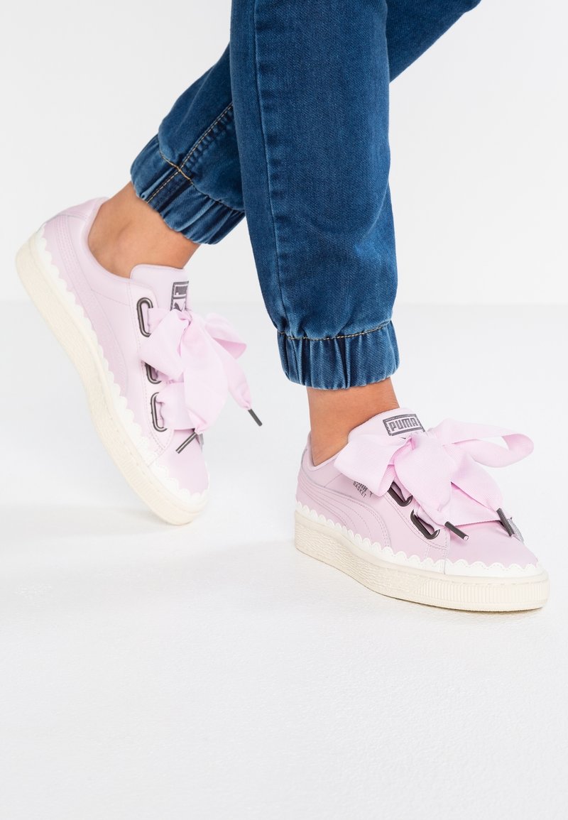 Rosa Sneakers mit großen Satin-Schleifen und gewellten Kanten, ausgestattet mit metallischen Ösen und einer strukturierten weißen Gummisohle.